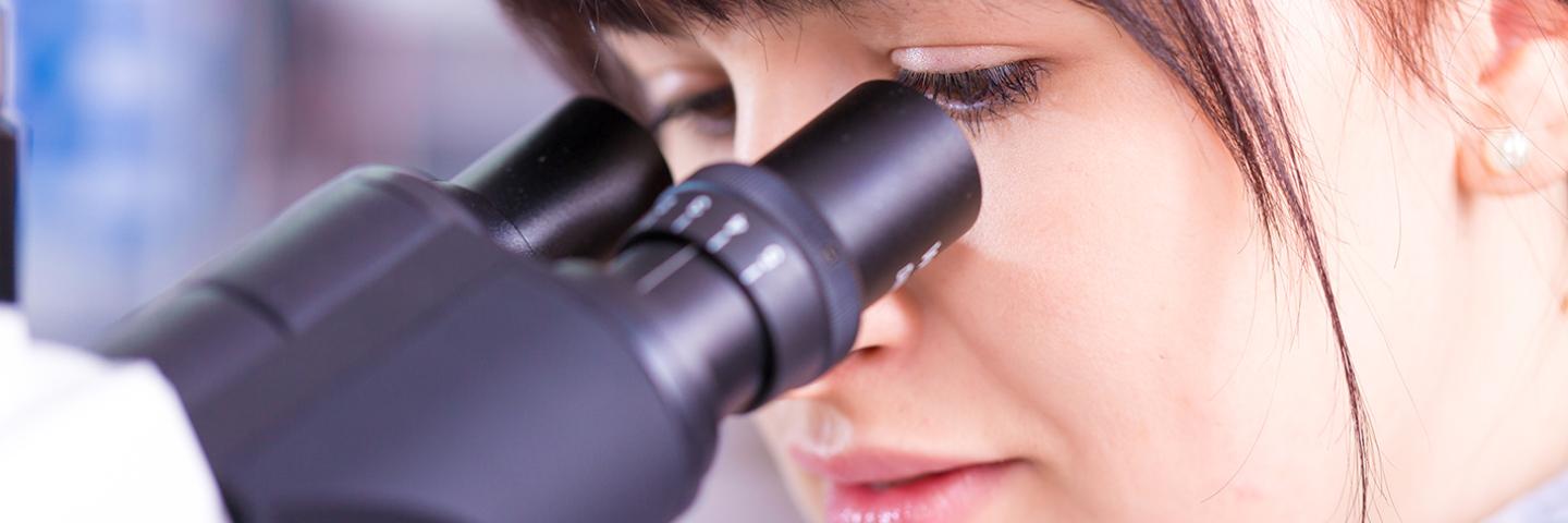 Photo of a women working on a microscope in a lab