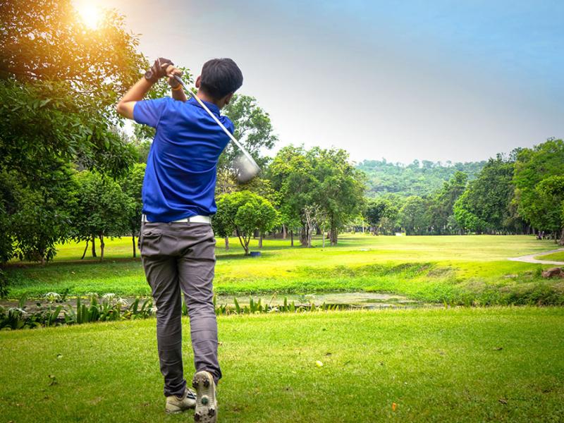 Male golfer swinging a club at the golf course 