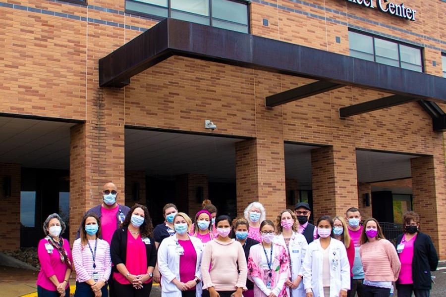 Employees gather for a breast cancer awareness photo dressed in pink.