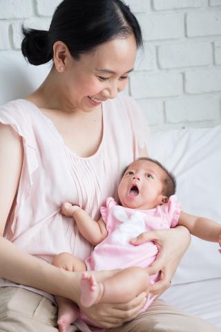 Photo of smiling mom holding newborn