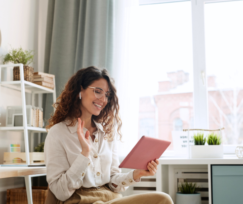 Woman looking into ipad and waving